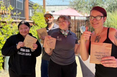 a group of smiling people outside enjoying bags of snacks