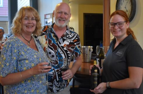 A few smiling people chatting and having a good time with glasses of wine.