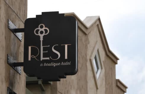 a brown sign on a hotel building that says REST a boutique hotel with a key as part of the E