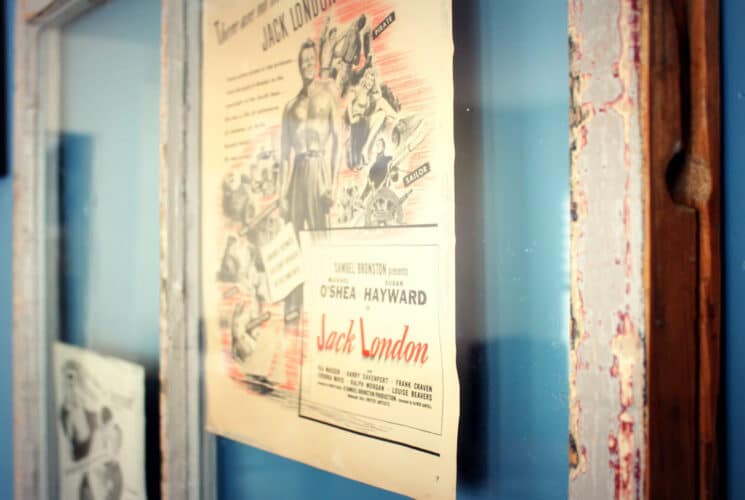 a blue wall with distressed window frames and antique book posters in the frames.