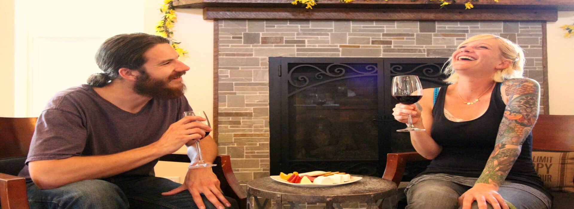 a man and a woman enjoying a glass of wine and conversation in front of a fireplace