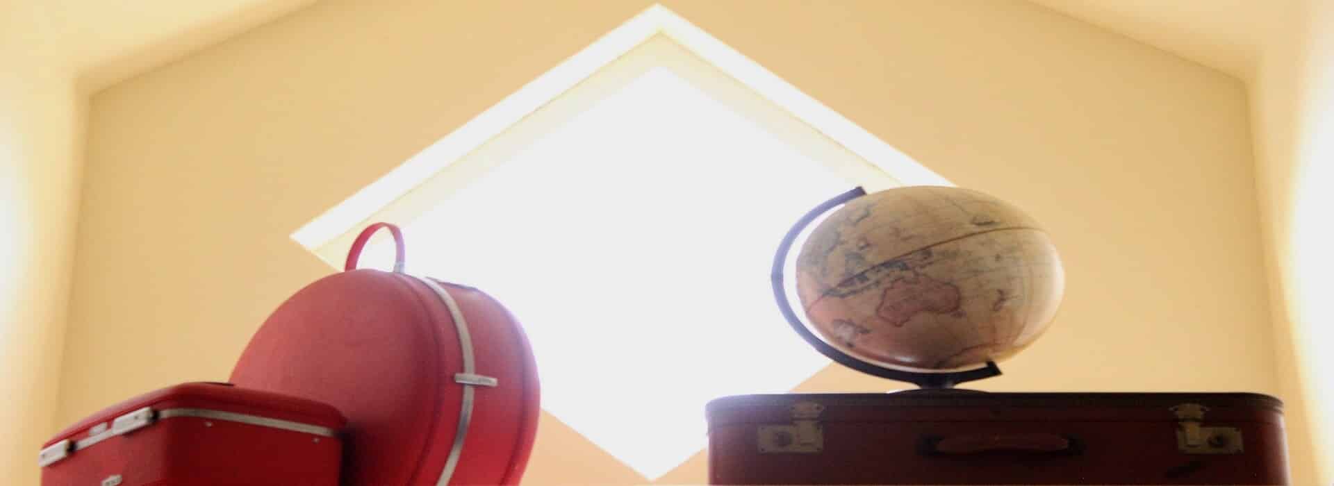 vintage suitcases and a globe in front of a diamond shaped window