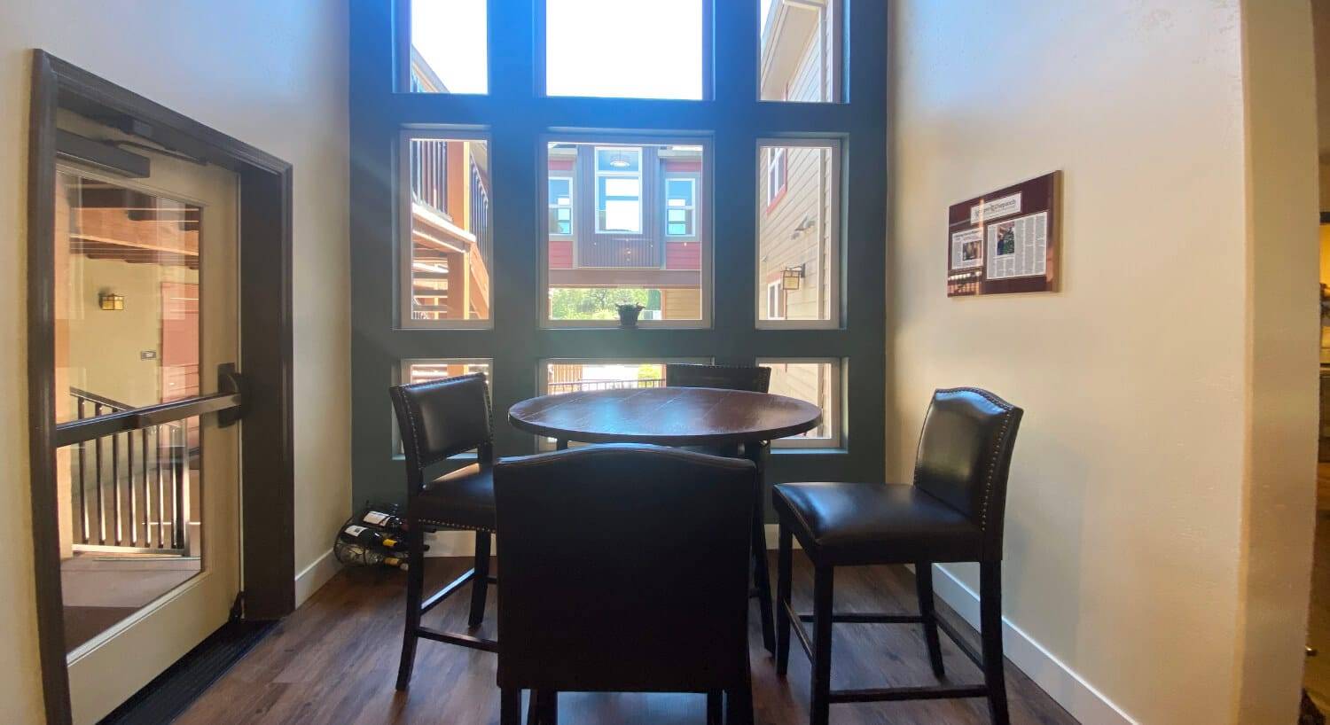 a small area in a hotel with a round table and chairs, with floor to ceiling windows